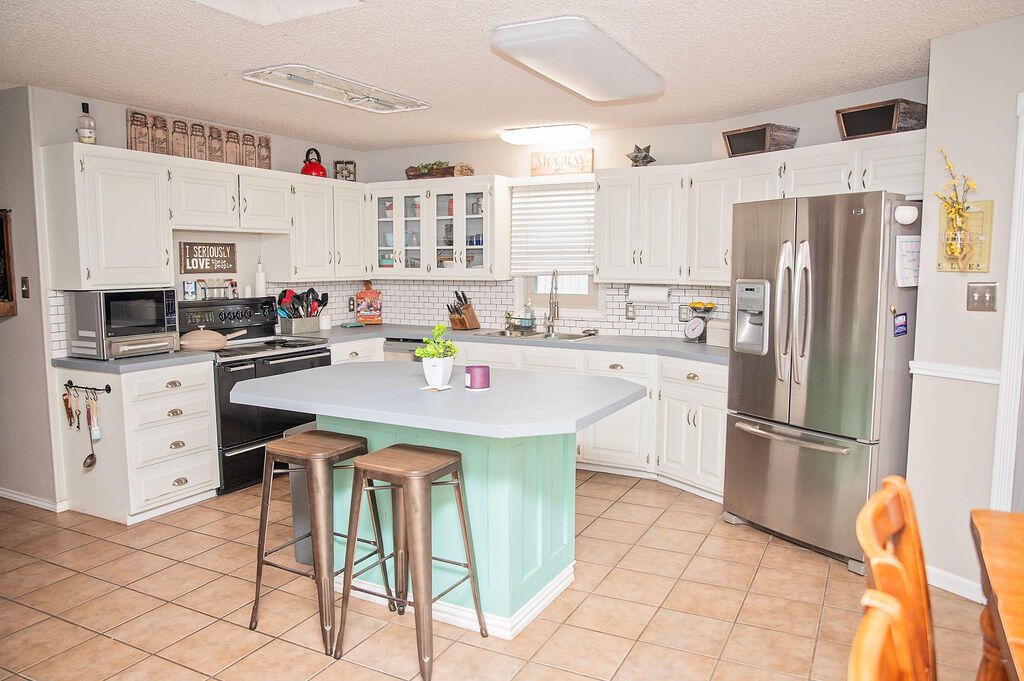 2917 Quail Ridge Road Denver City, TX 79323 - Photo 9 of 55 a kitchen with stainless steel appliances a white refrigerator a sink a stove a dining table and chairs