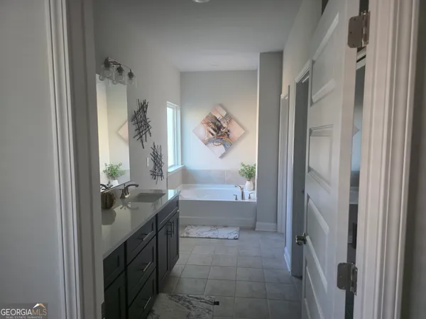 a en suite bathroom with a granite countertop sink a mirror and a bathtub