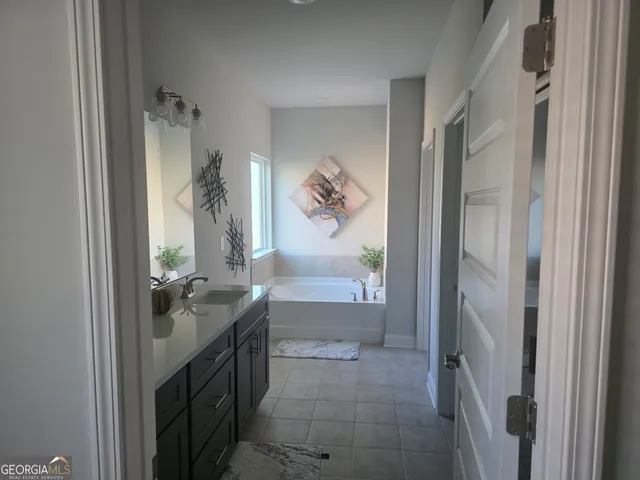 a en suite bathroom with a granite countertop sink a mirror and a bathtub