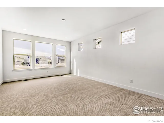 a view of an empty room with a window and kitchen view
