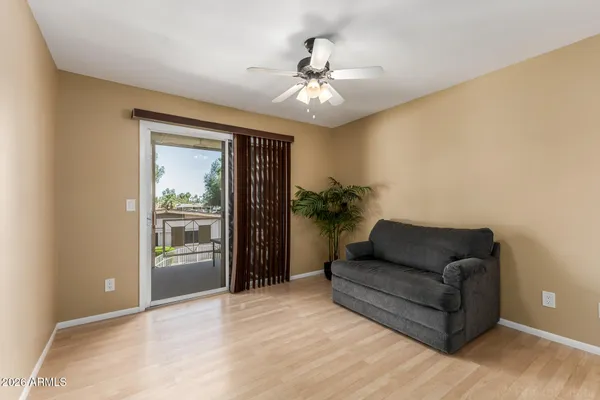 a view of an empty room with wooden floor and a ceiling fan