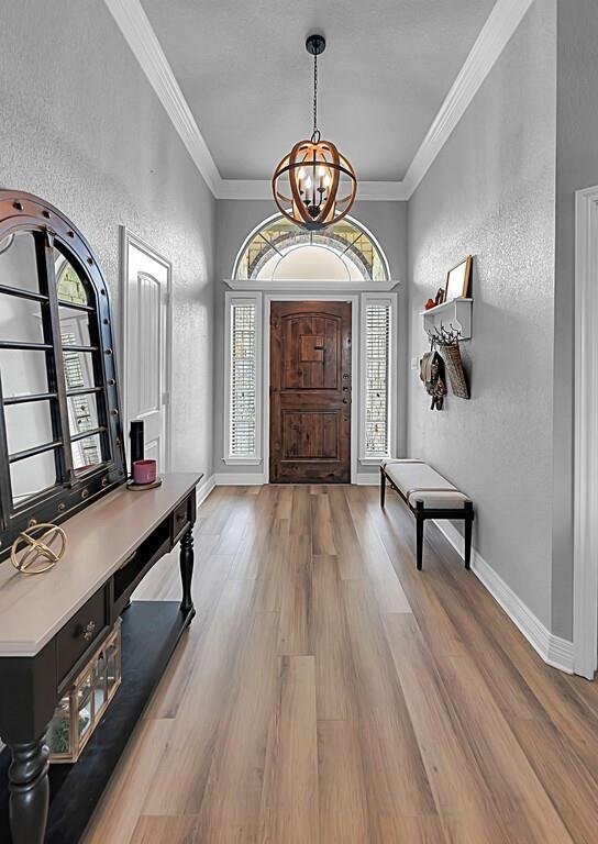 550 Hunton Lane Robinson, TX 76706 - Photo 4 of 35 Entrance foyer with a textured wall, a chandelier, plenty of natural light, wood finished floors, and ornamental molding