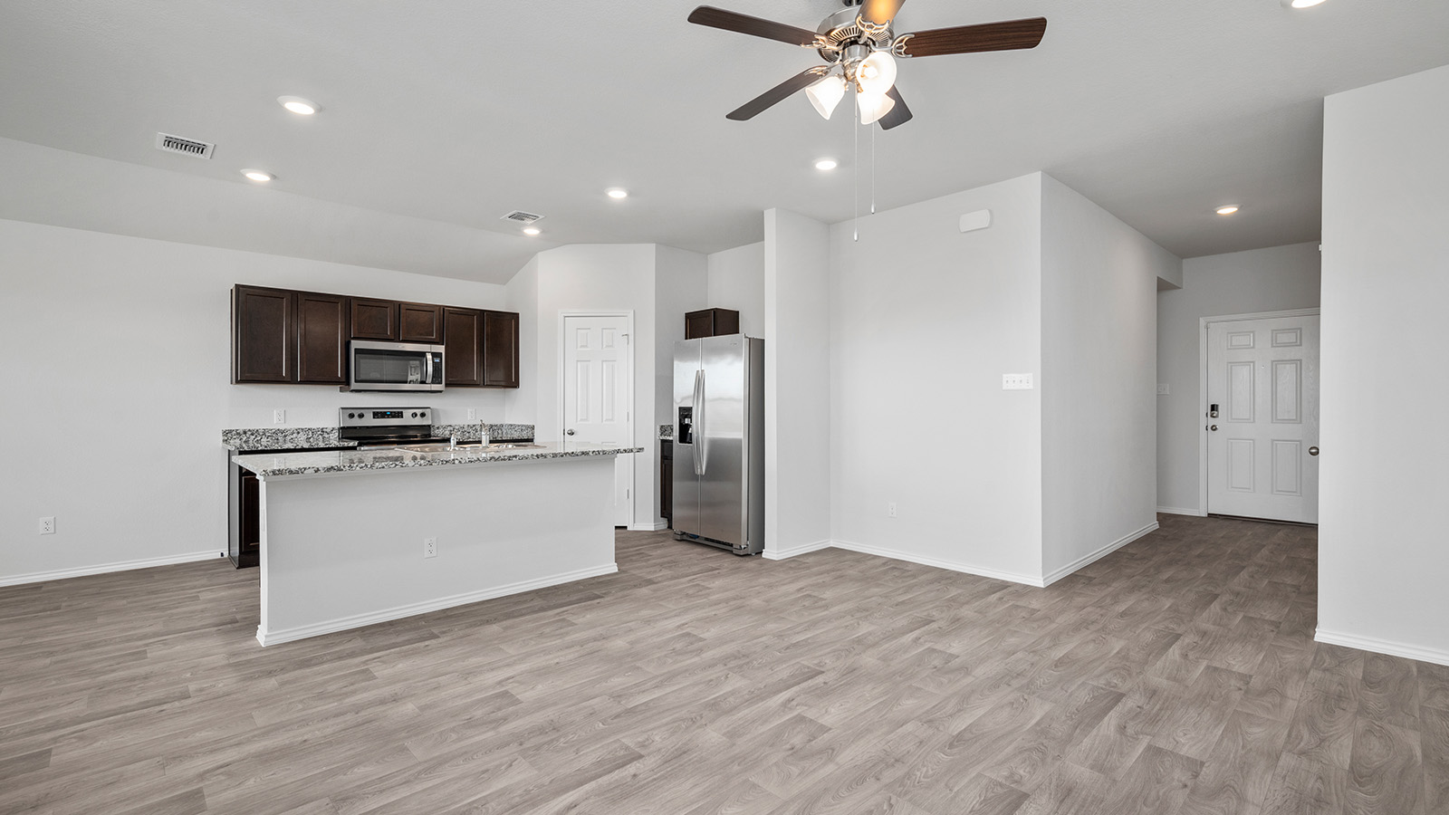 1311 Victory Rnch Trail Killeen, TX 76549 - Photo 9 of 22 Kitchen with dark wood finish cabinetry, stainless steel appliances, a center island with sink, ceiling fan, and light wood-style floors