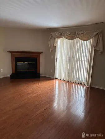 an empty room with wooden floor fireplace and windows