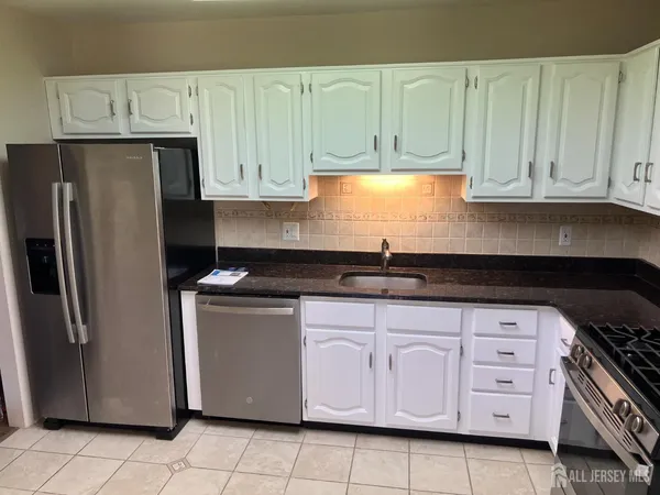 a kitchen with stainless steel appliances granite countertop a refrigerator a stove a sink and dishwasher