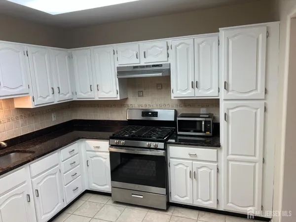 a kitchen with white cabinets and appliances