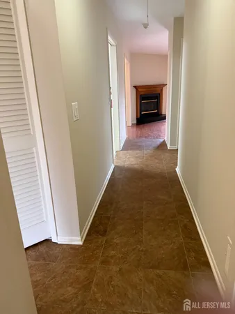 a view of a hallway to an empty room with a fireplace