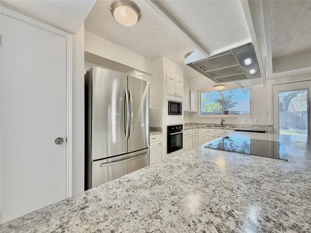 a kitchen with granite countertop a refrigerator and a sink