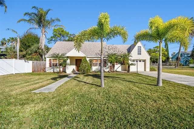 a view of a house with a yard and palm trees