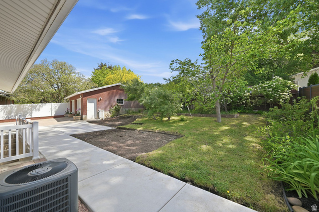 3120 North Apache Way Provo, UT 84604 - Photo 48 of 58 Spacious concrete patio and walkways extending to a detached brick outbuilding with multiple doors, surrounded by established trees and green landscaping