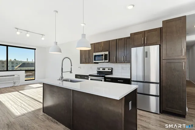 a kitchen with kitchen island a counter top space cabinets and stainless steel appliances