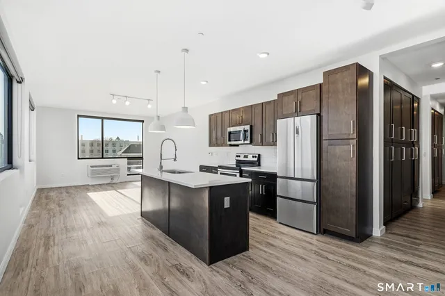 a kitchen with stainless steel appliances a refrigerator a stove a sink cabinets and wooden floor