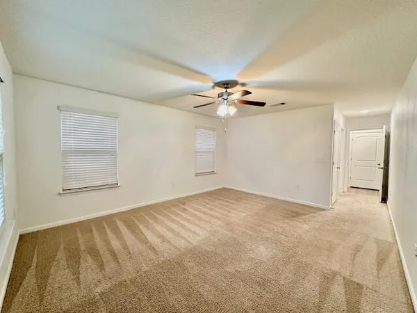 an empty room with windows and ceiling fan view