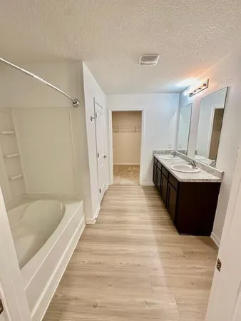 a bathroom with a granite countertop sink a mirror and a bathtub