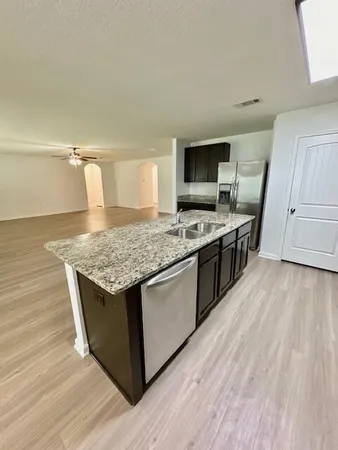 a large kitchen with stainless steel appliances granite countertop a stove a sink dishwasher and a refrigerator with wooden floor