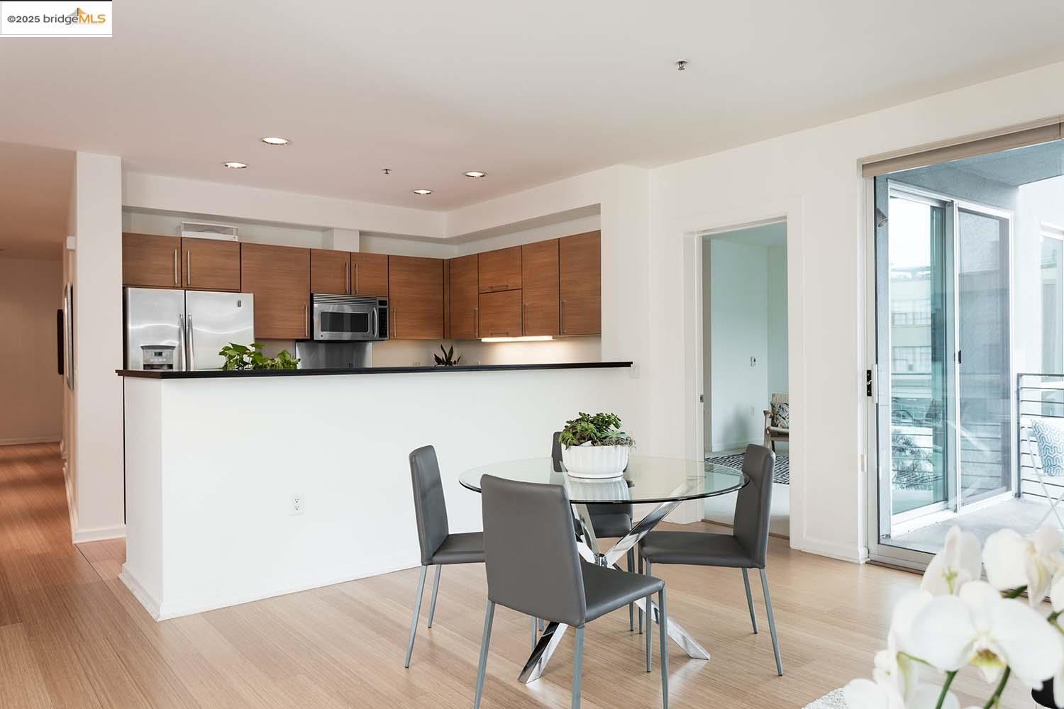 200 2nd Street, Unit 215 Oakland, CA 94607 - Photo 3 of 18 a kitchen with stainless steel appliances granite countertop a dining table chairs and a refrigerator