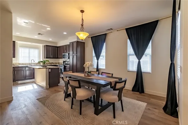 a kitchen with stainless steel appliances a dining table chairs refrigerator and sink