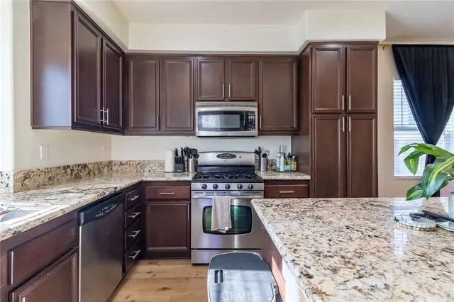 a kitchen with stainless steel appliances granite countertop a stove a sink dishwasher and a refrigerator