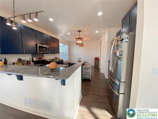 a kitchen with stainless steel appliances granite countertop a refrigerator a stove a sink dishwasher and a refrigerator with wooden floor