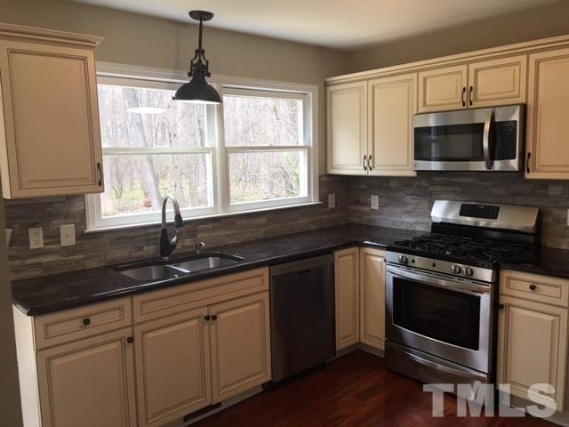 8105 Greywinds Drive Raleigh, NC 27615 - Photo 3 of 18 a kitchen with granite countertop a stove a sink and a microwave