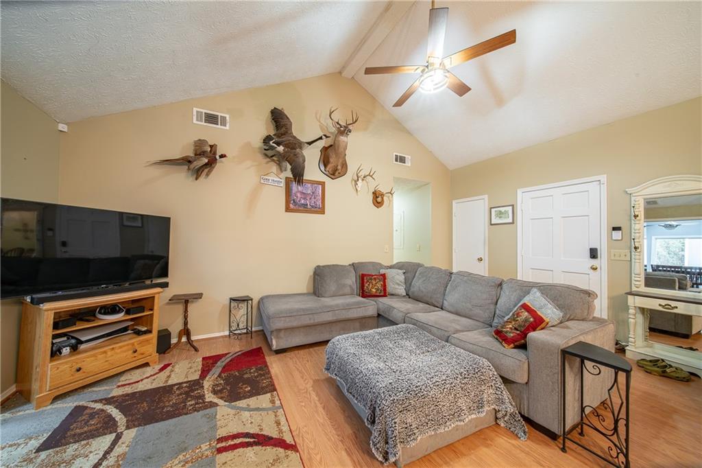 143 Lee Road 979 Phenix City, AL 36870 - Photo 22 of 37 Living room featuring ceiling fan, light hardwood / wood-style flooring, lofted ceiling with beams, and a textured ceiling