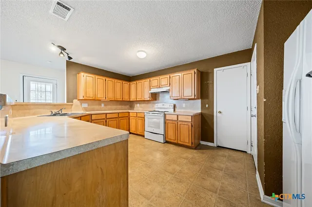 a large kitchen with stainless steel appliances granite countertop a sink and cabinets