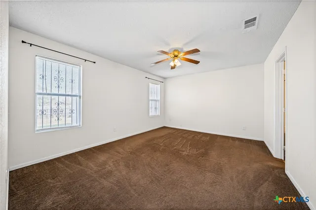 an empty room with a window and a fan