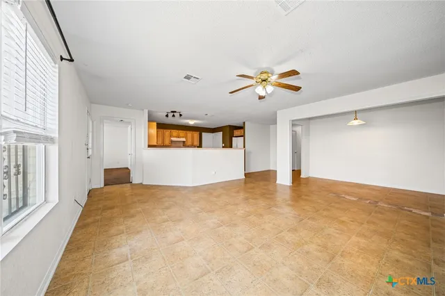 an empty room with a window and a ceiling fan