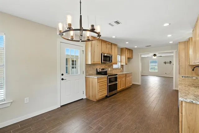 a kitchen with stainless steel appliances granite countertop a refrigerator a stove oven a sink dishwasher and white cabinets with wooden floor