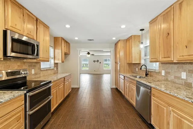 a large kitchen with stainless steel appliances granite countertop a stove a sink and a microwave