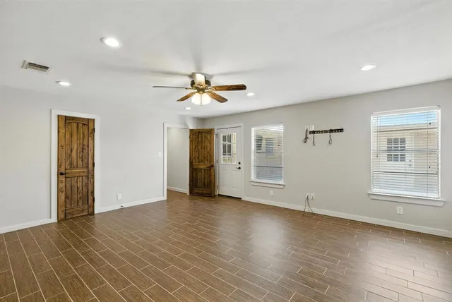 an empty room with wooden floor and windows