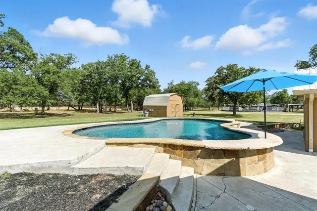 a view of a swimming pool with a patio and a yard