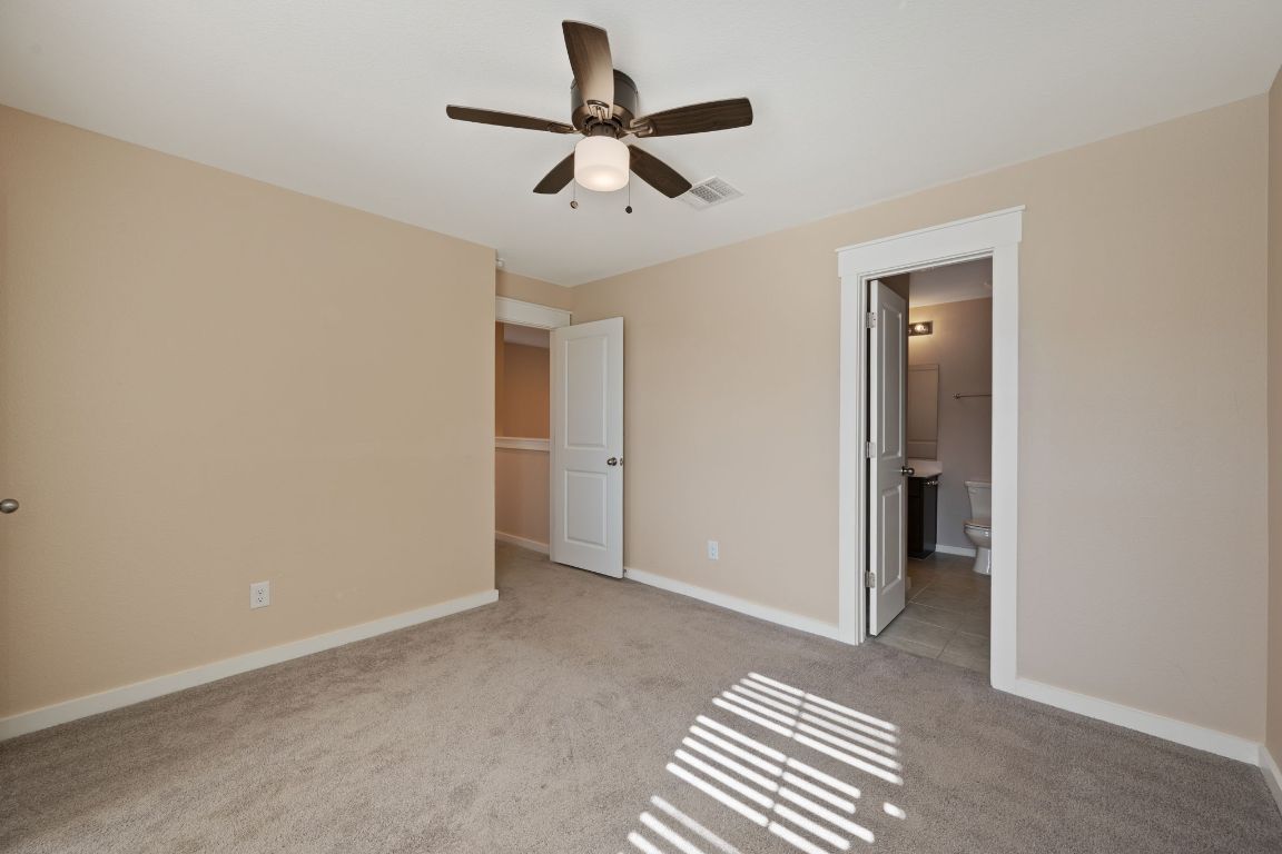 602 Knopper Street, Unit B Pflugerville, TX 78660 - Photo 19 of 26 Unfurnished bedroom featuring light colored carpet, ceiling fan, and ensuite bath