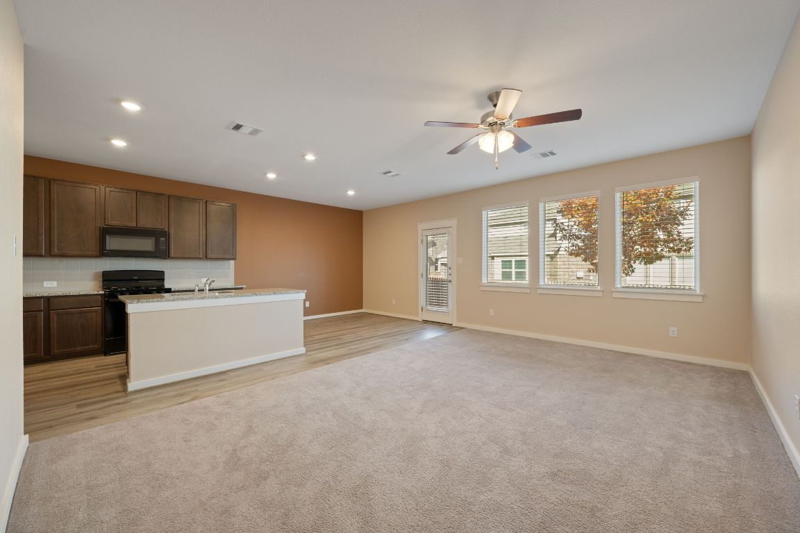 602 Knopper Street, Unit B Pflugerville, TX 78660 - Photo 25 of 26 Kitchen featuring an island with sink, open floor plan, black appliances, light colored carpet, and recessed lighting