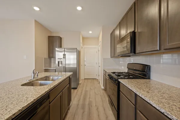 a kitchen with stainless steel appliances granite countertop a sink a stove a refrigerator a washer and dryer