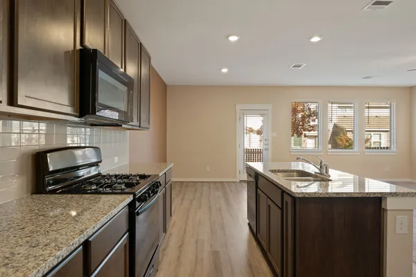 a kitchen with granite countertop stainless steel appliances a sink stove top oven and cabinets