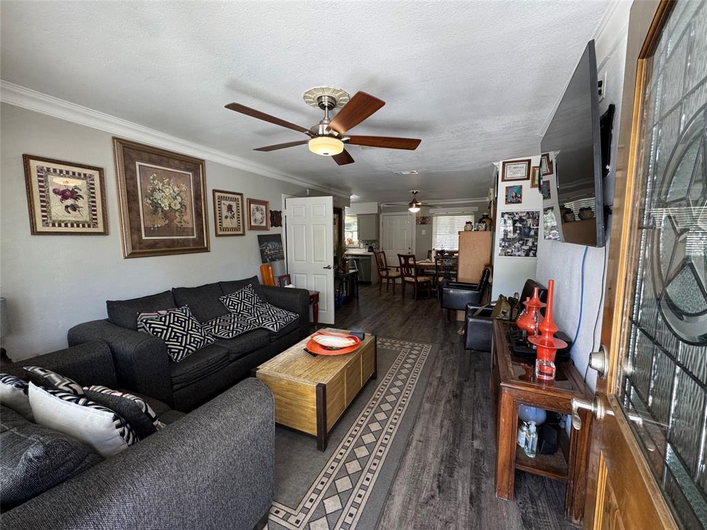 320 Pecan Street Wilmer, TX 75172 - Photo 3 of 25 Living room featuring dark wood-style floors, ornamental molding, a ceiling fan, and a textured ceiling