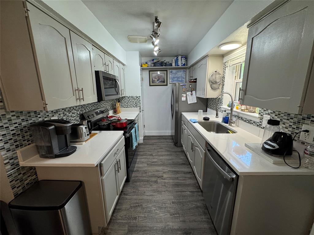 320 Pecan Street Wilmer, TX 75172 - Photo 7 of 25 Kitchen with backsplash, stainless steel appliances, and dark wood-style floors