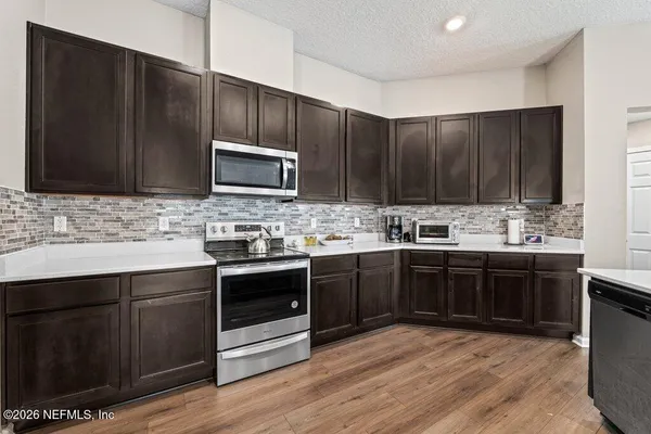 a kitchen with stainless steel appliances kitchen island granite countertop wooden cabinets and a stove top oven