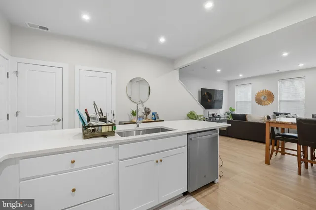 a living room with stainless steel appliances kitchen island granite countertop a sink and wooden floor