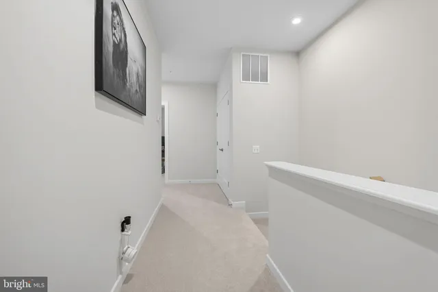 a view of a hallway with wooden floor and a bathroom