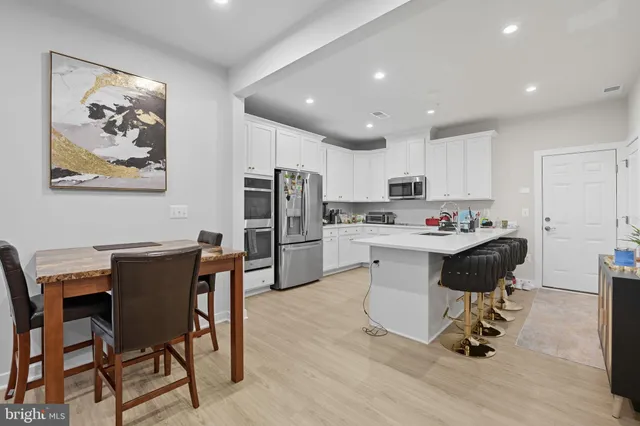 a kitchen with a refrigerator cabinets a dining table and chairs with wooden floor