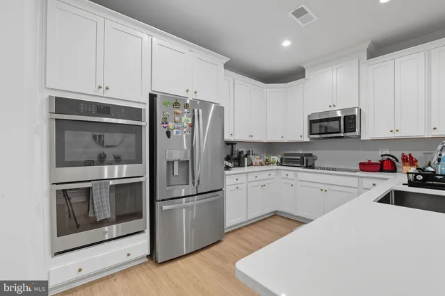 a kitchen with granite countertop white cabinets and stainless steel appliances