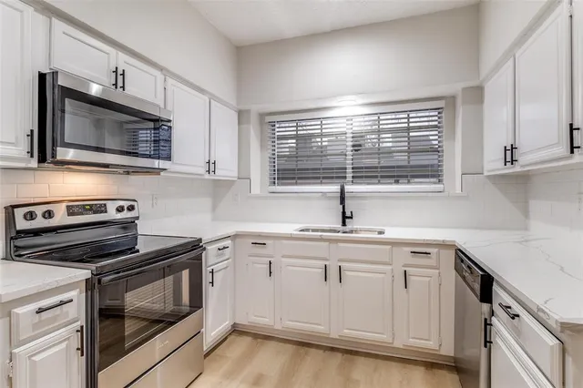 a kitchen with cabinets stainless steel appliances a sink and a window