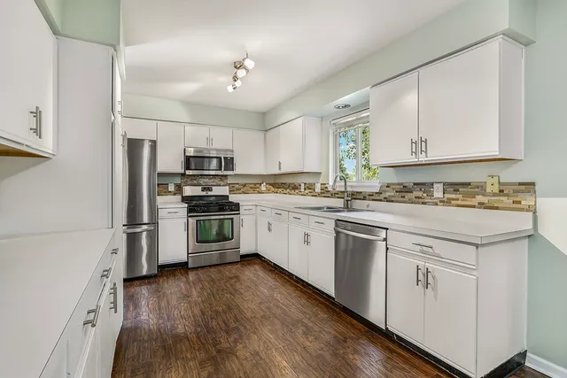 a kitchen with granite countertop white cabinets and stainless steel appliances