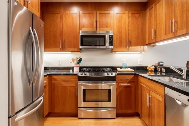 a kitchen with stainless steel appliances granite countertop a stove a sink and a microwave