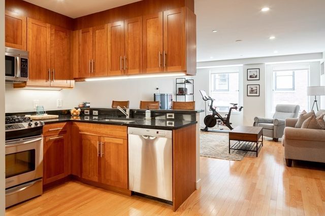 a kitchen with stainless steel appliances granite countertop wooden cabinets a sink a stove a dining table and chairs