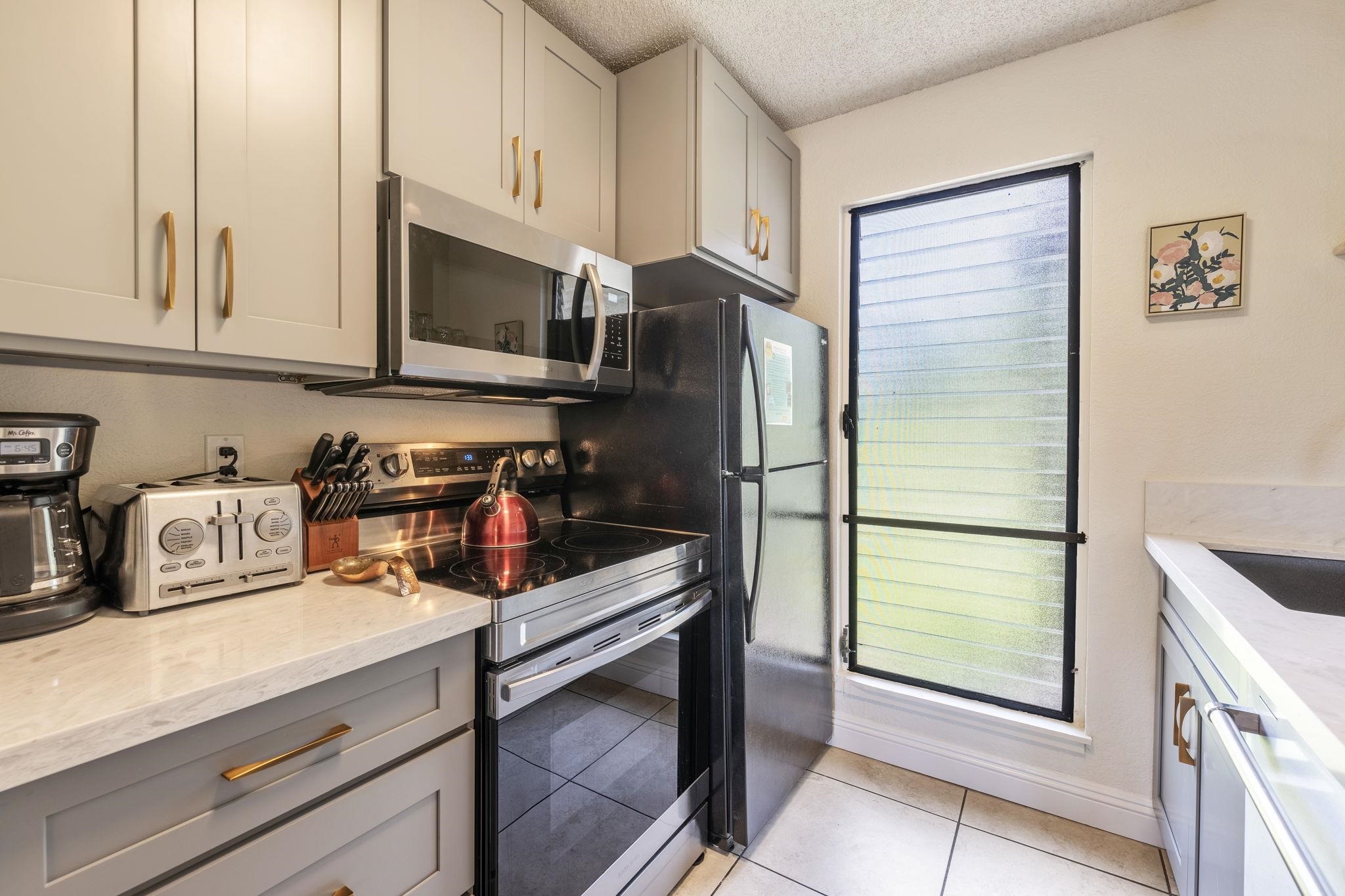 2881 South Kihei Road, Unit 59 Kihei, HI 96753 - Photo 10 of 37 a kitchen with stainless steel appliances granite countertop a refrigerator a stove and a sink