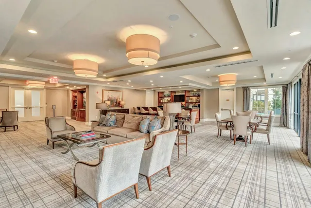 a living room with lots of chairs and kitchen view
