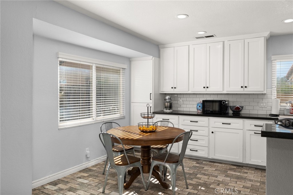 18165 Mariposa Avenue Riverside, CA 92508 - Photo 10 of 59 a kitchen with stainless steel appliances kitchen island granite countertop a table chairs sink and cabinets